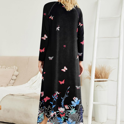 Person wearing a black dress with colorful butterfly patterns in a room.