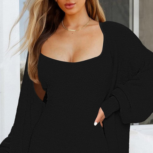 Woman wearing a black outfit with a gold necklace against a neutral background