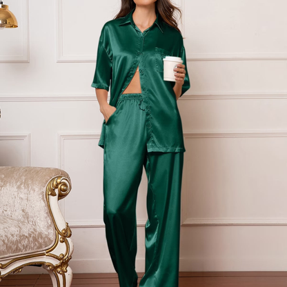 Person wearing a green satin pajama set holding a coffee cup in a room with decorative elements.