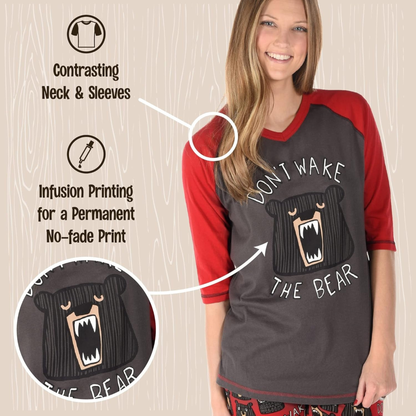 Woman wearing a black and red shirt with bear graphic and text, on a wooden background.