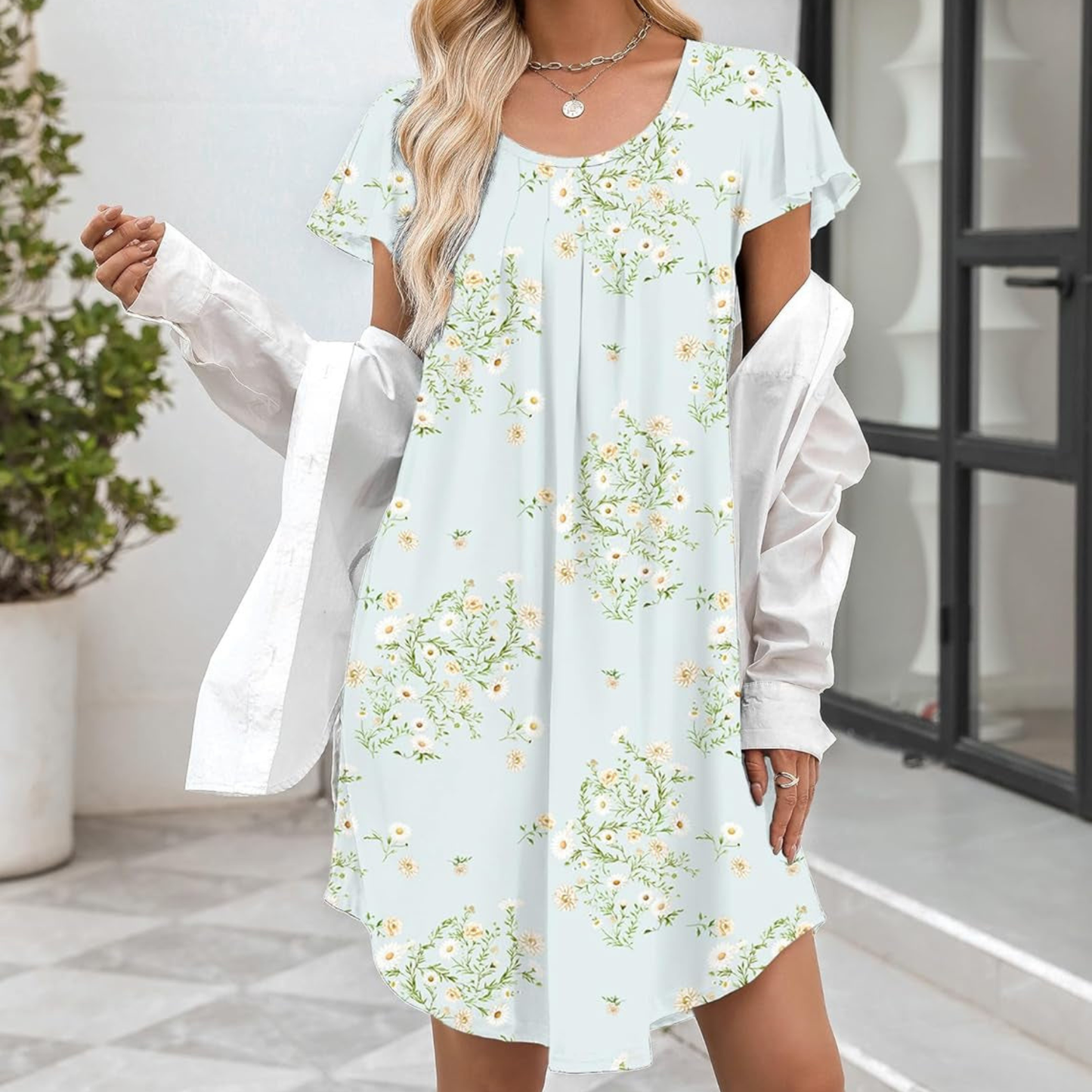 Woman wearing a light blue floral dress with sheer sleeves in an indoor setting.