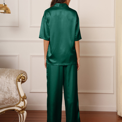 Person wearing a green satin pajama set in a room with a decorative chair.