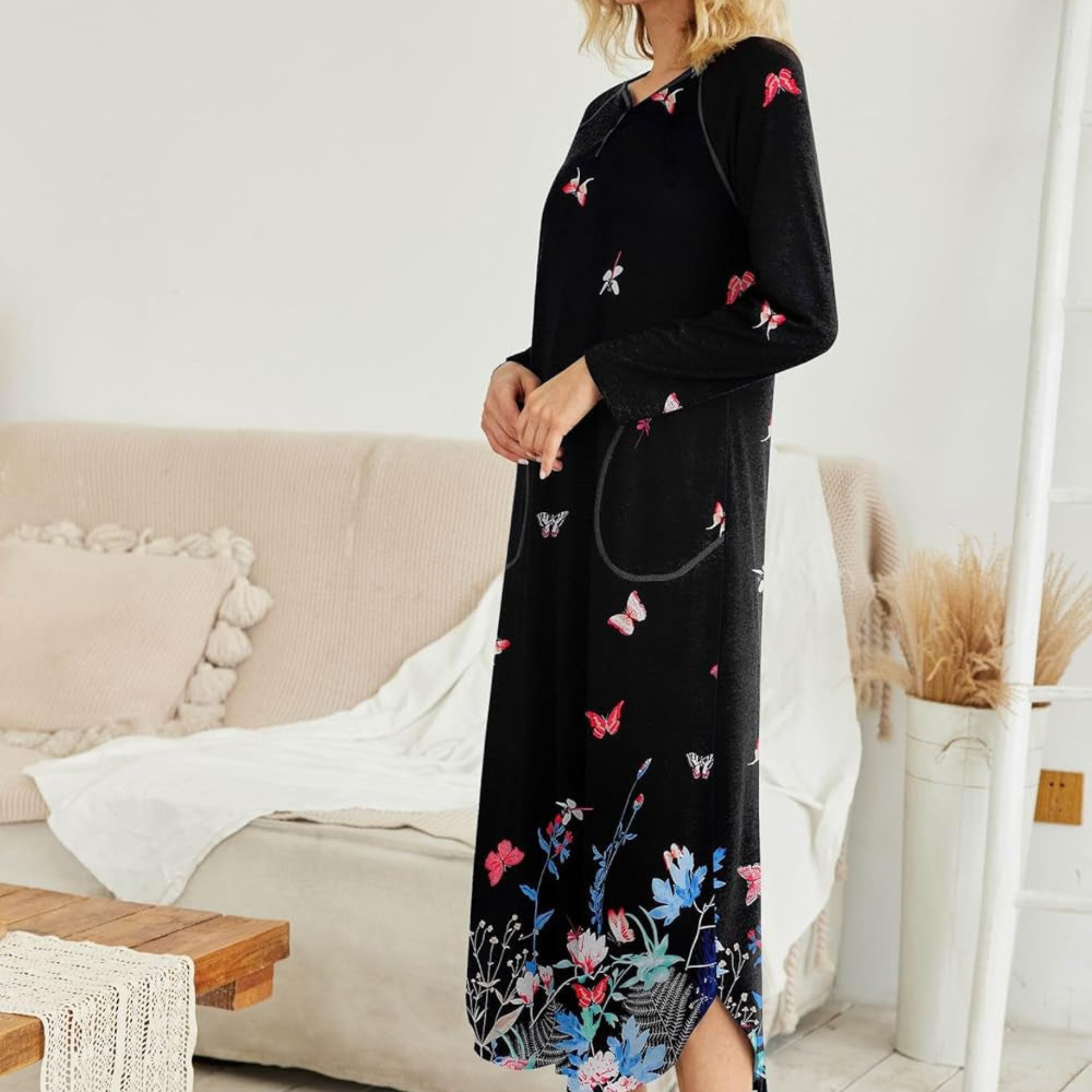 Woman wearing a black dress with floral and butterfly patterns in a living room setting.