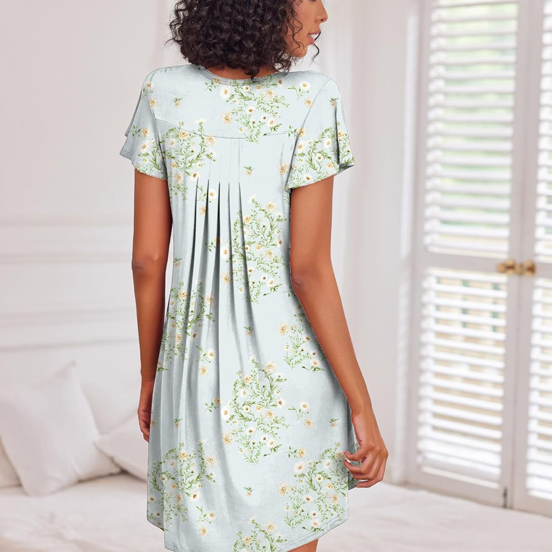 Woman wearing a light blue floral dress in a bright room.