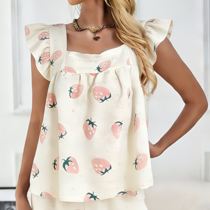 Woman wearing a white top with strawberry pattern on a plain background