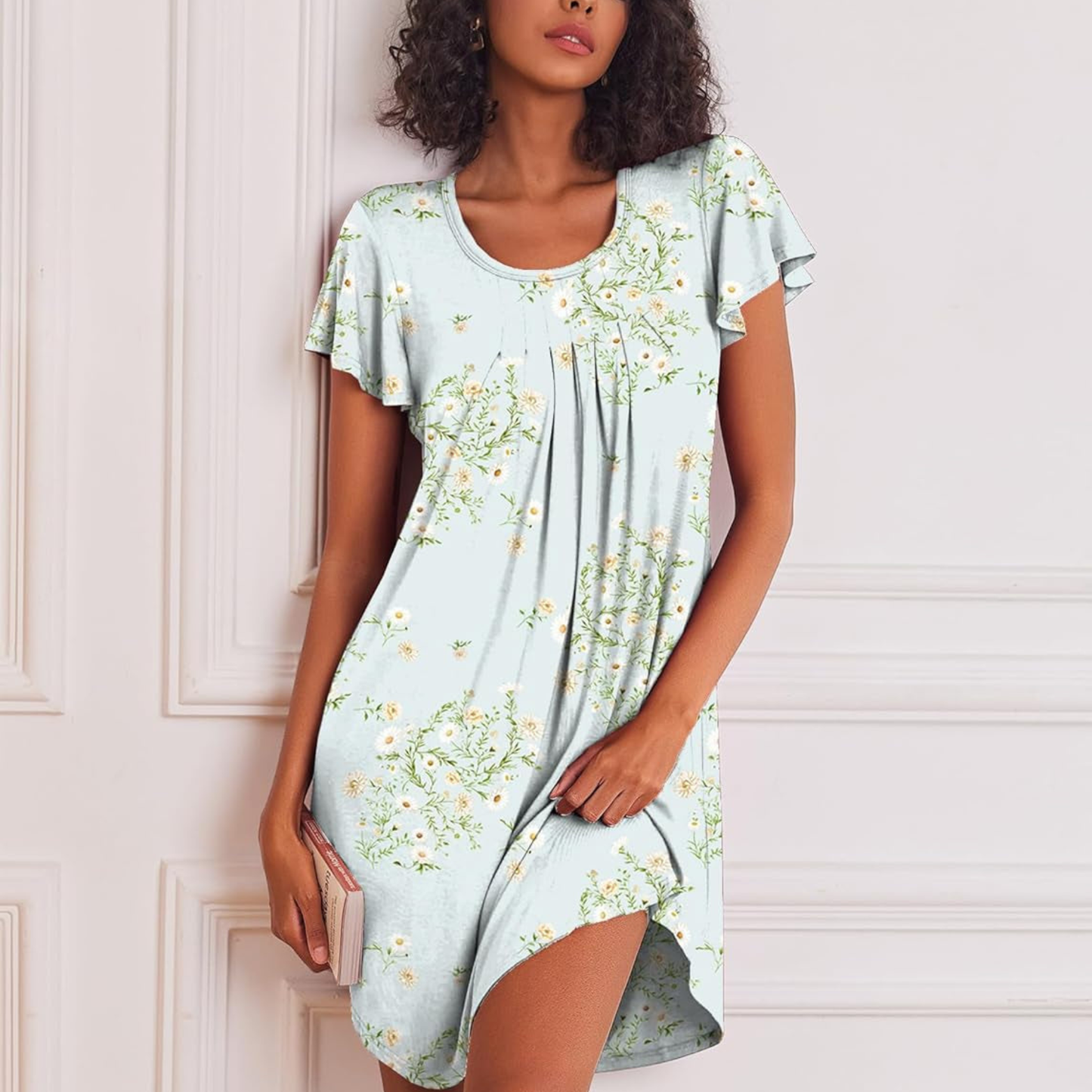 Woman wearing a light blue floral dress against a white wall