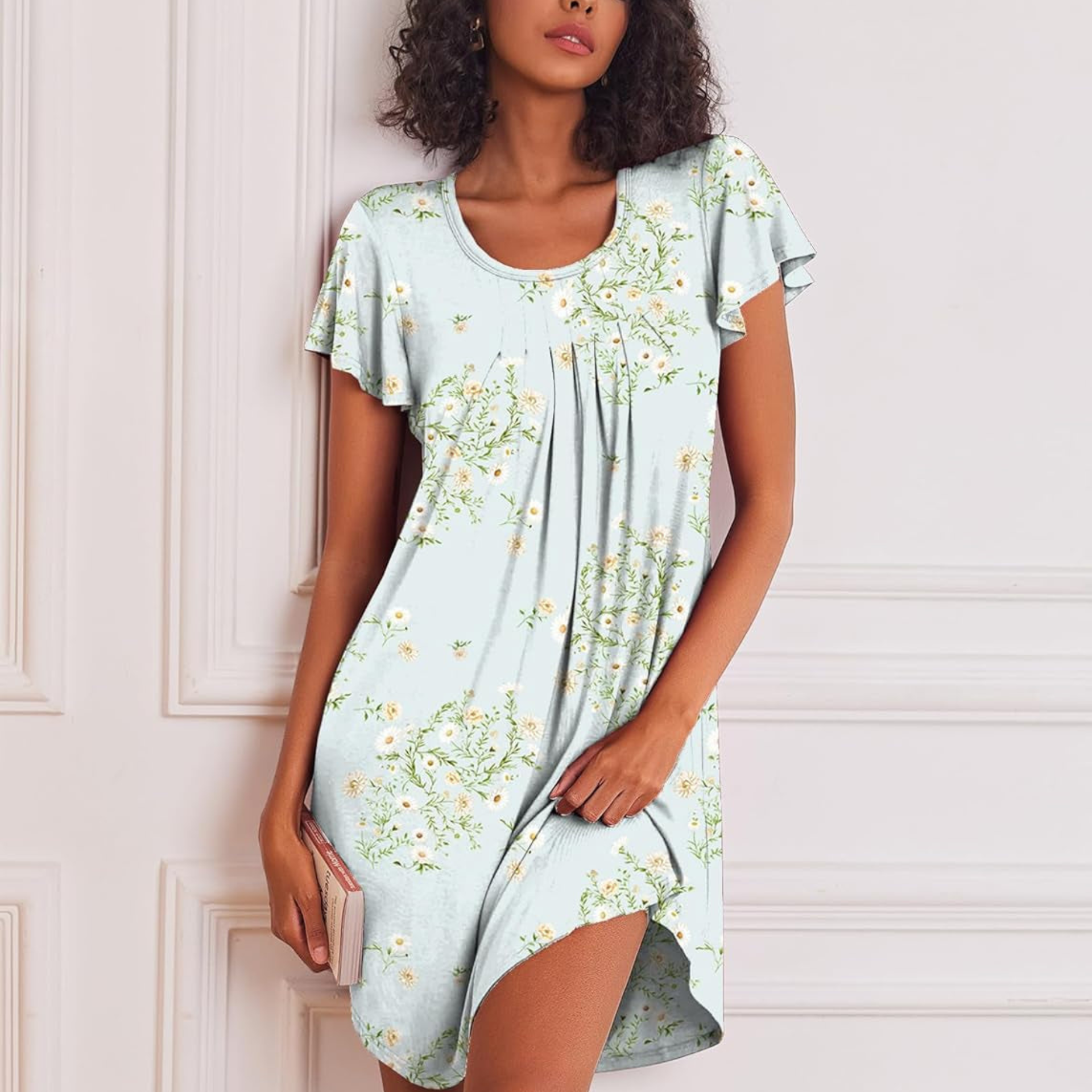 Woman wearing a light blue floral dress against a white wall