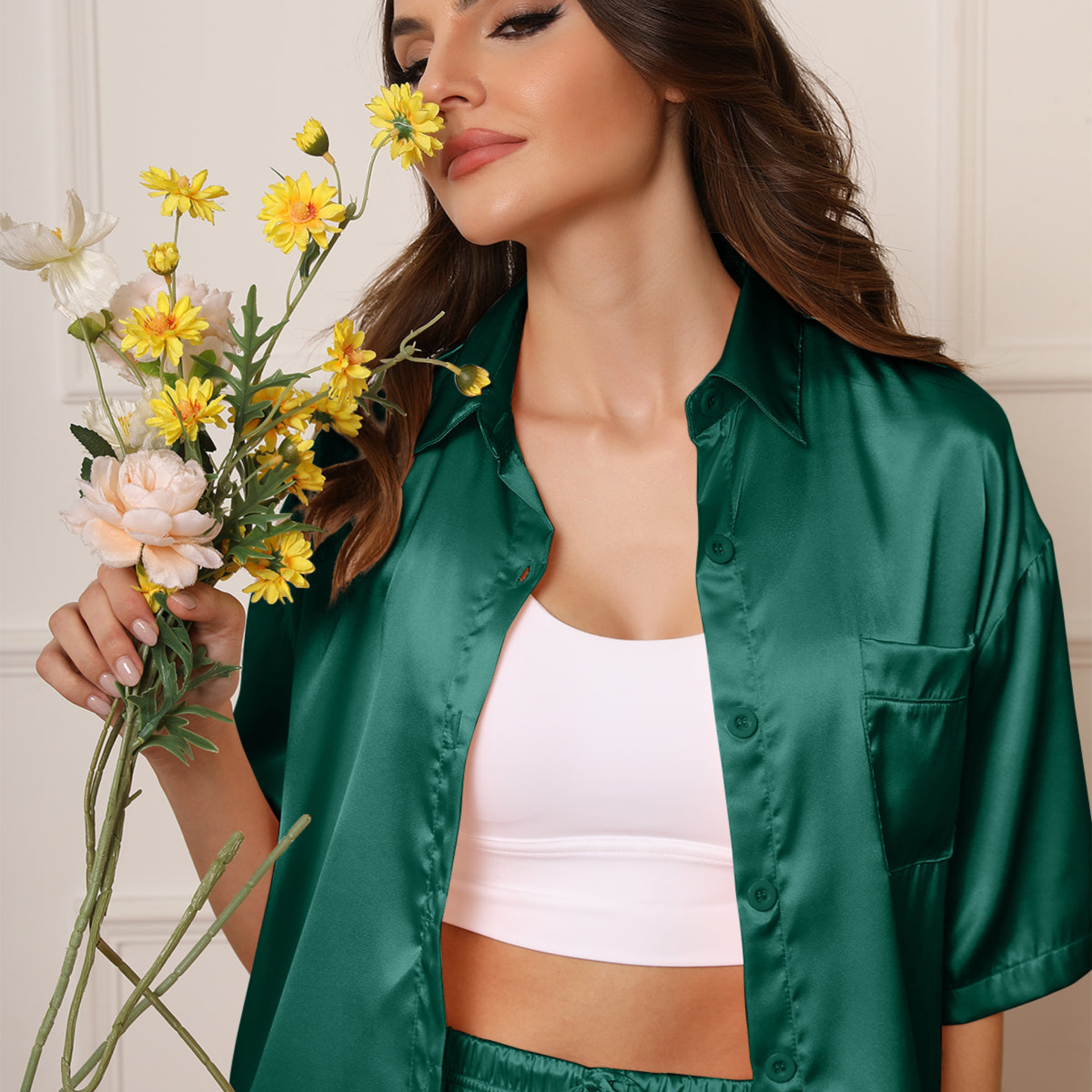 Woman wearing a green satin shirt holding a bouquet of flowers.